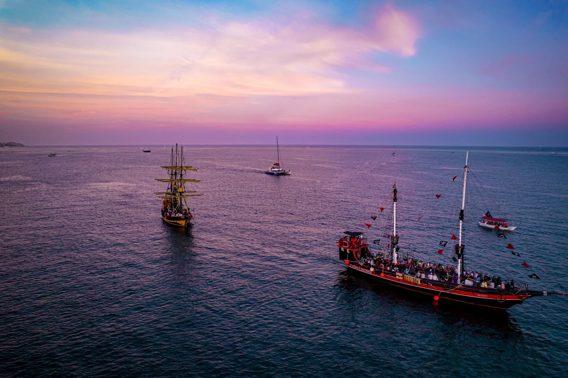 Pirate ship sailing past Land's End arch at sunset in Cabo San Lucas Bay