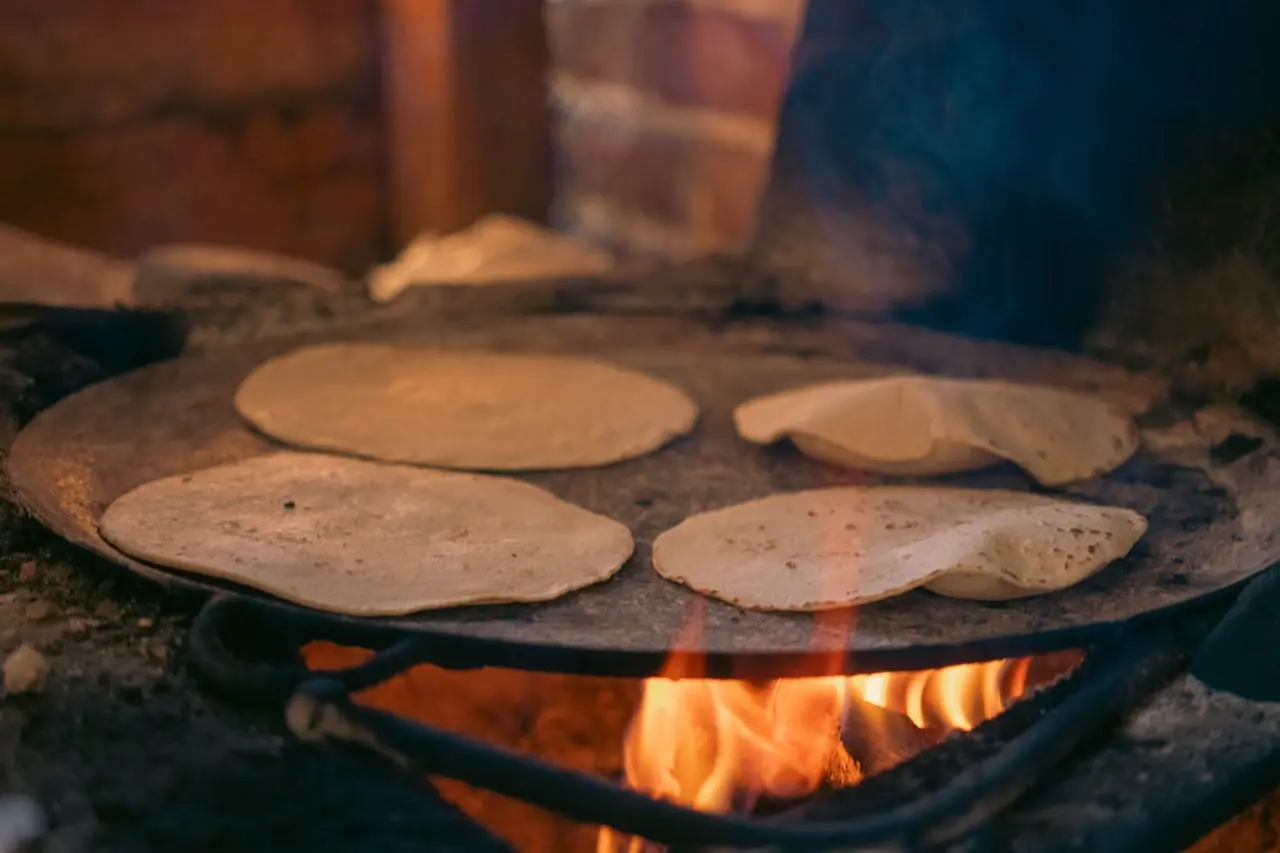 Hands shaping fresh corn tortillas beside salsas and chiles at a Cabo San Lucas cooking class