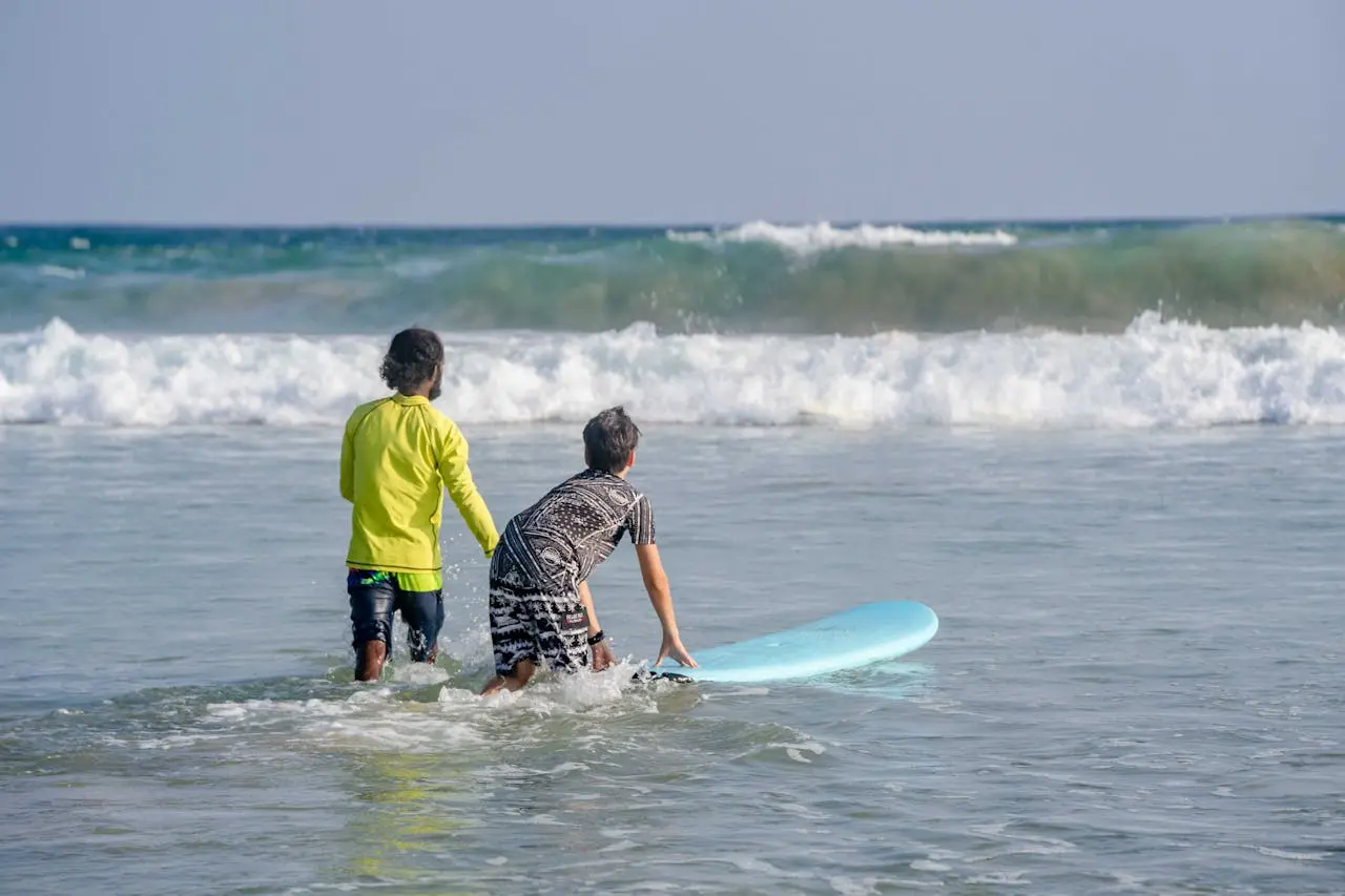 Beginner surfer riding a small wave at Costa Azul beach near Cabo San Lucas with an instructor watching from the water
